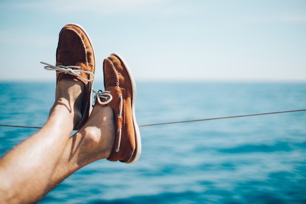 Photo of man legs on the yacht and wearing boat shoes. Horizontal mockup